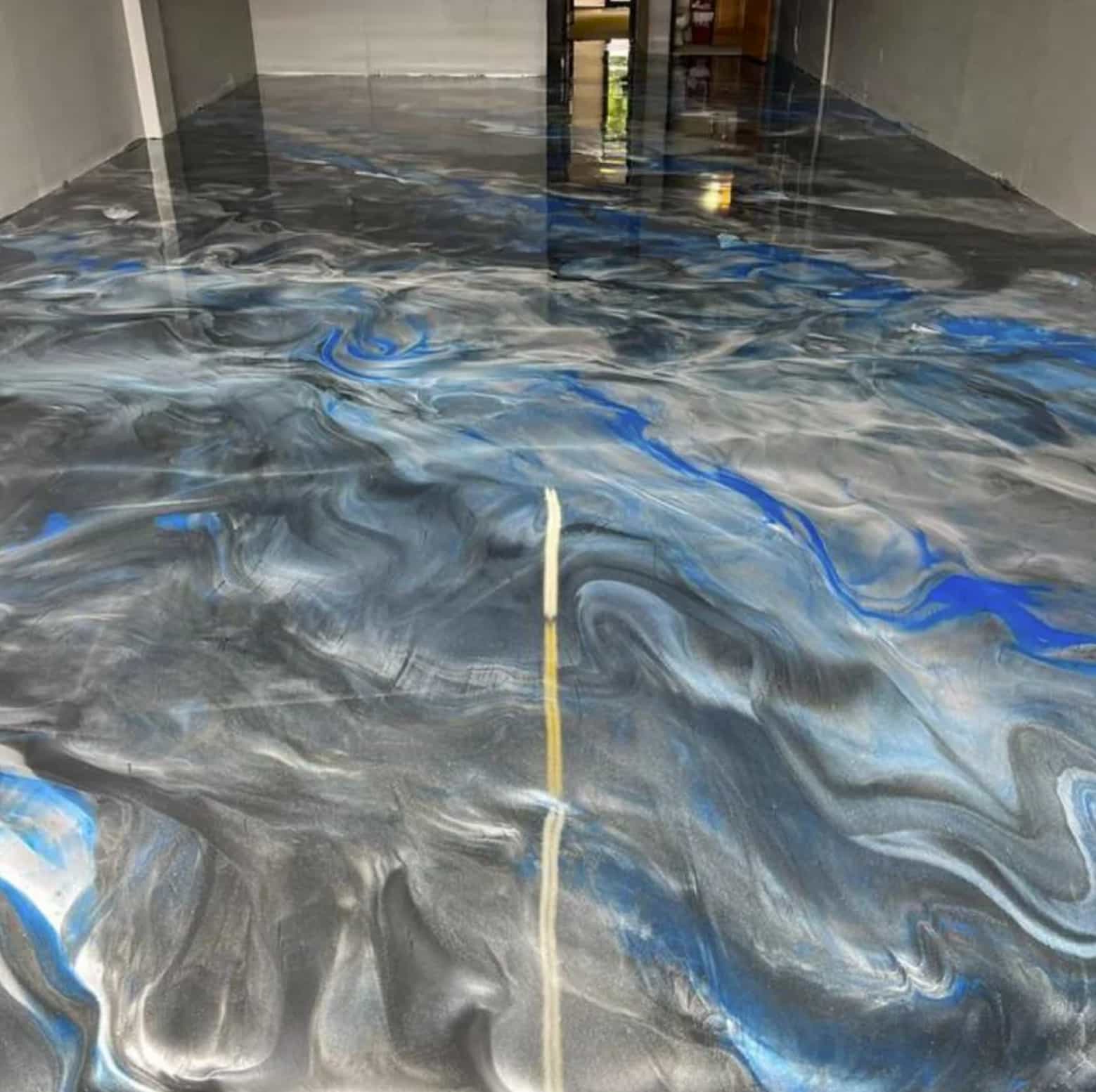 Indoor floor with a glossy, swirling epoxy finish in black, gray, white, and blue colors.