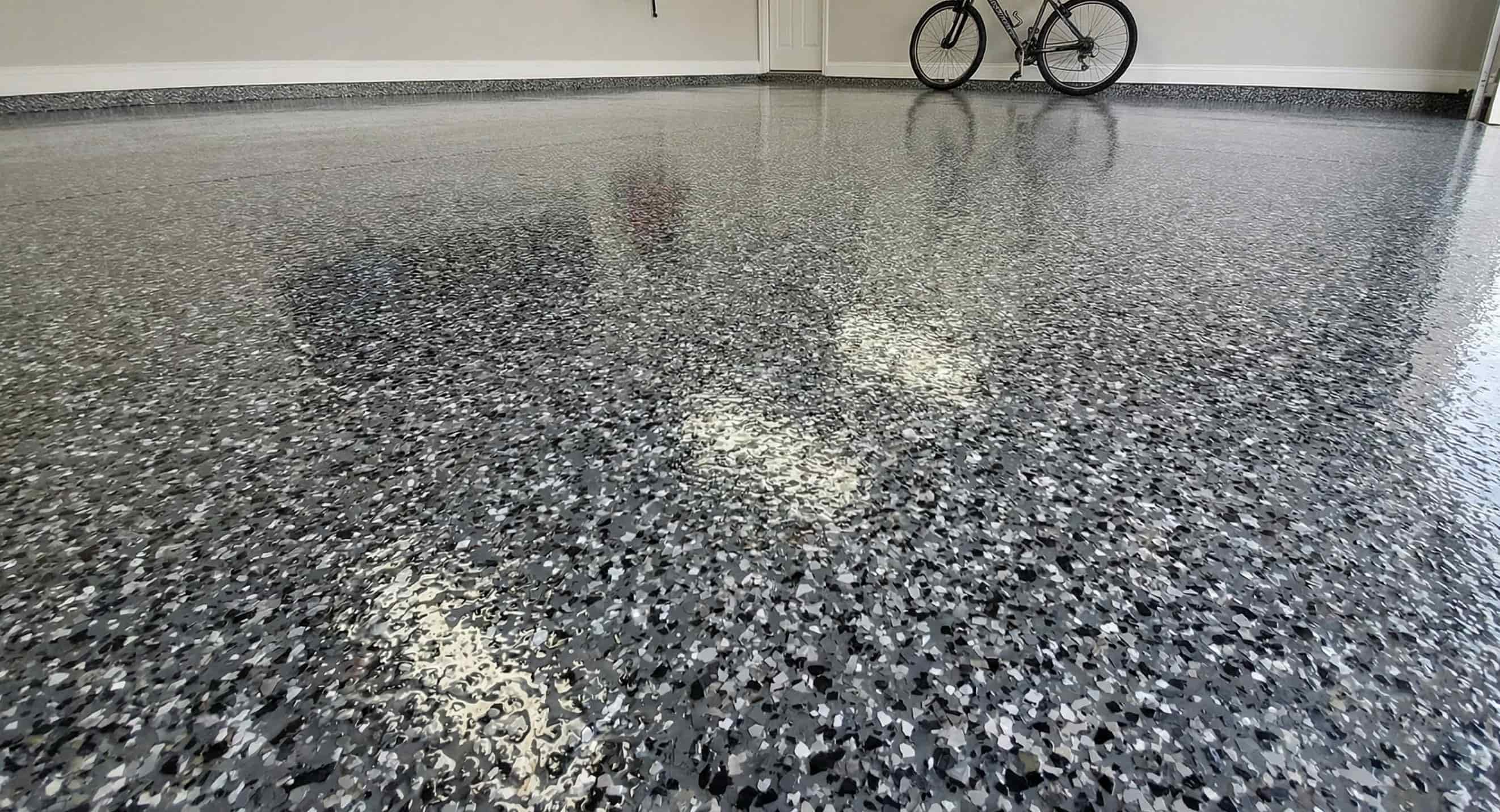 Glossy speckled epoxy-coated garage floor with a bicycle leaning against the wall in the background.