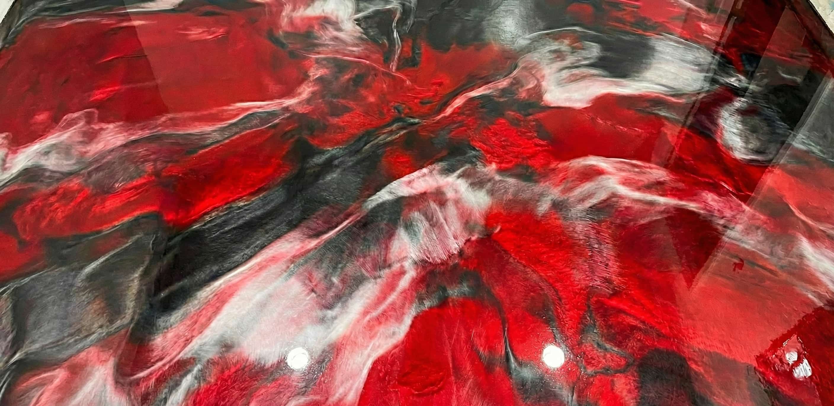 Glossy epoxy resin floor with swirling patterns in red, black, and white.