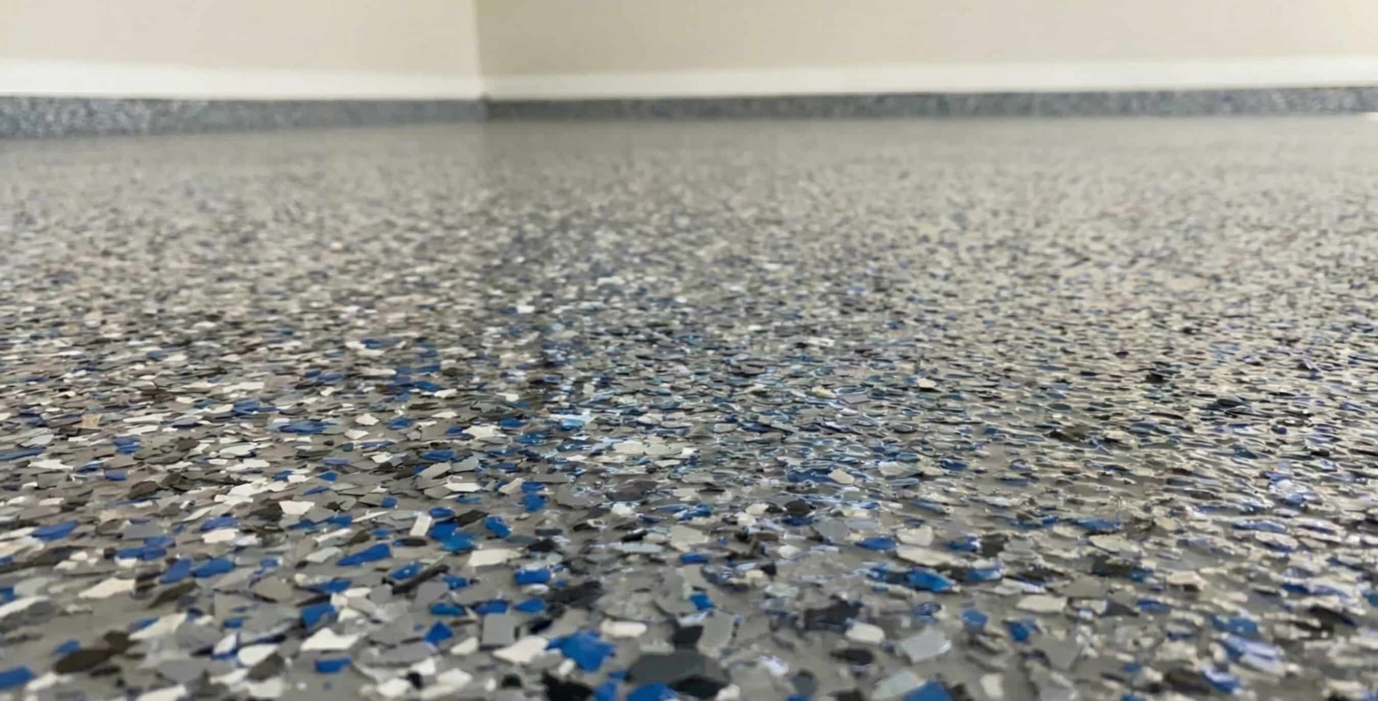 Close-up of a speckled epoxy floor with gray, blue, white, and black flakes.