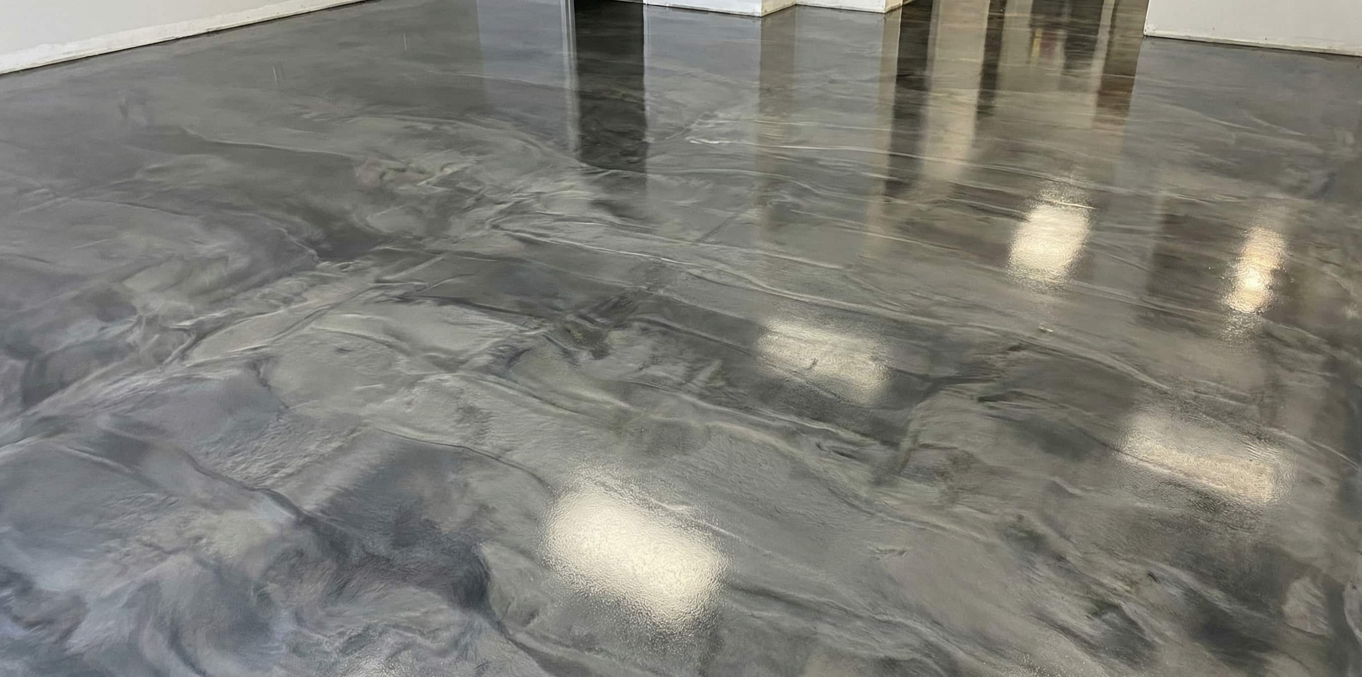 Polished concrete floor with a reflective, marbled gray and black finish in an empty room.