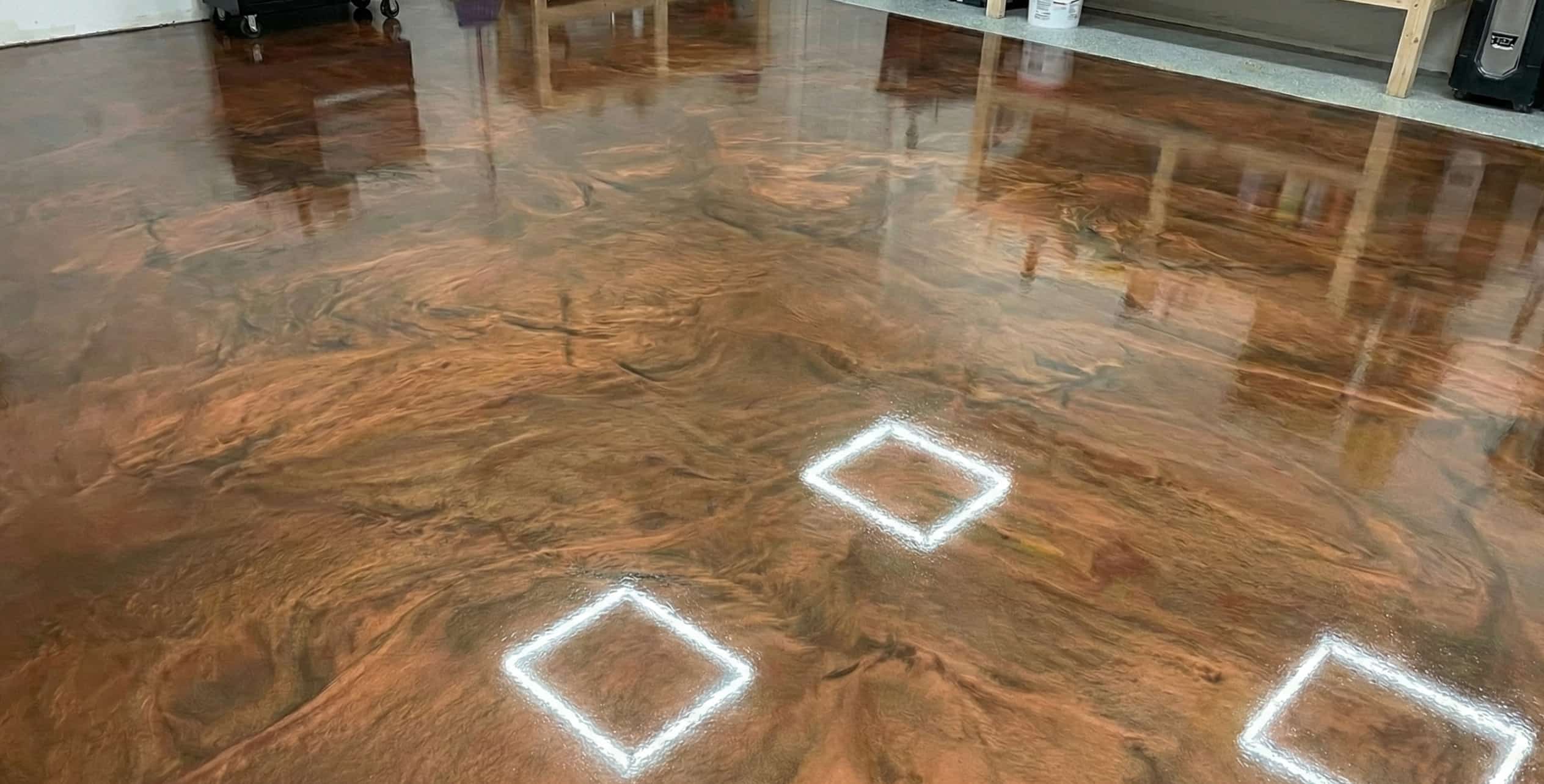 Glossy epoxy floor with a marbled brown and copper swirl pattern and three white square markings.