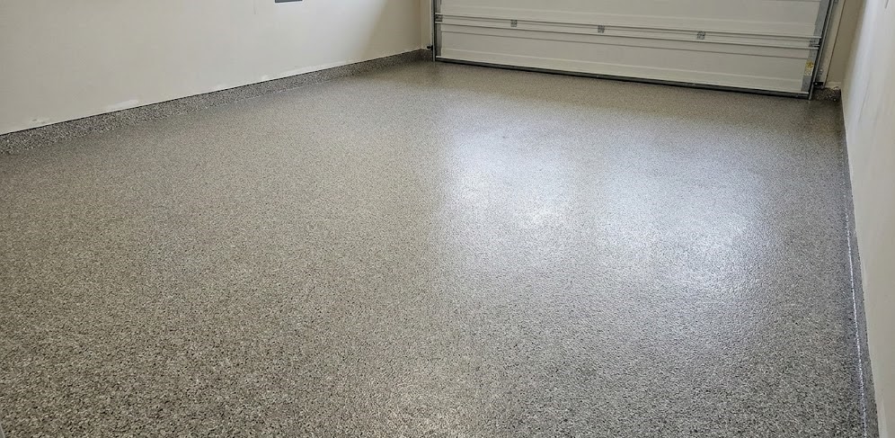 Empty garage with clean, speckled epoxy floor and closed white garage door.