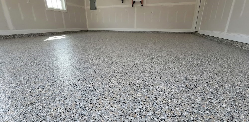 Empty garage interior with clean, speckled epoxy-coated floor and unfinished drywall walls.