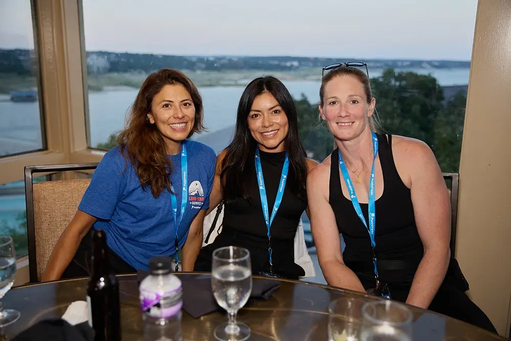Three PushPress female employees sitting together at a table.