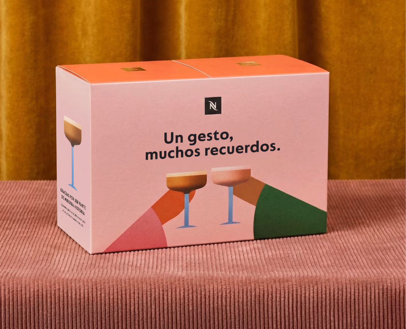 Pink box with Nespresso logo and text in Spanish showing two illustrated hands toasting with glasses.
