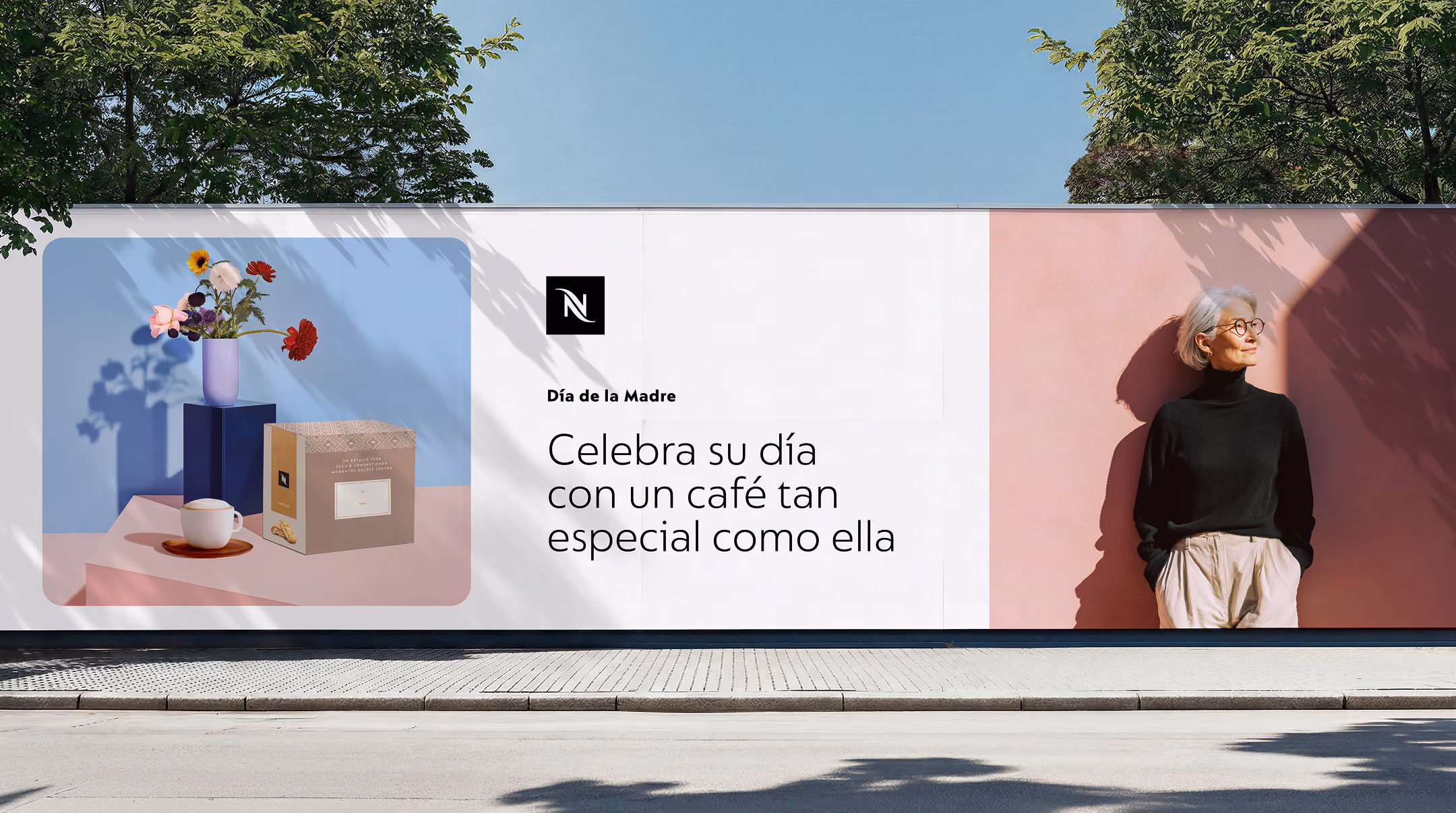 Billboard ad showing a coffee gift box, cup, and flowers with a senior woman standing against a pink wall.