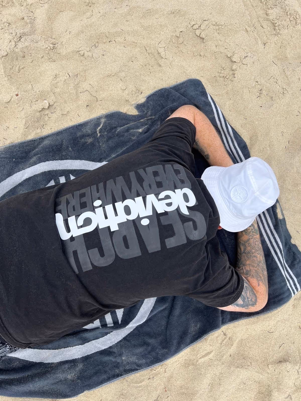 a picture showing Ashley Liddell on a beach, wearing a 'search everywhere' tee