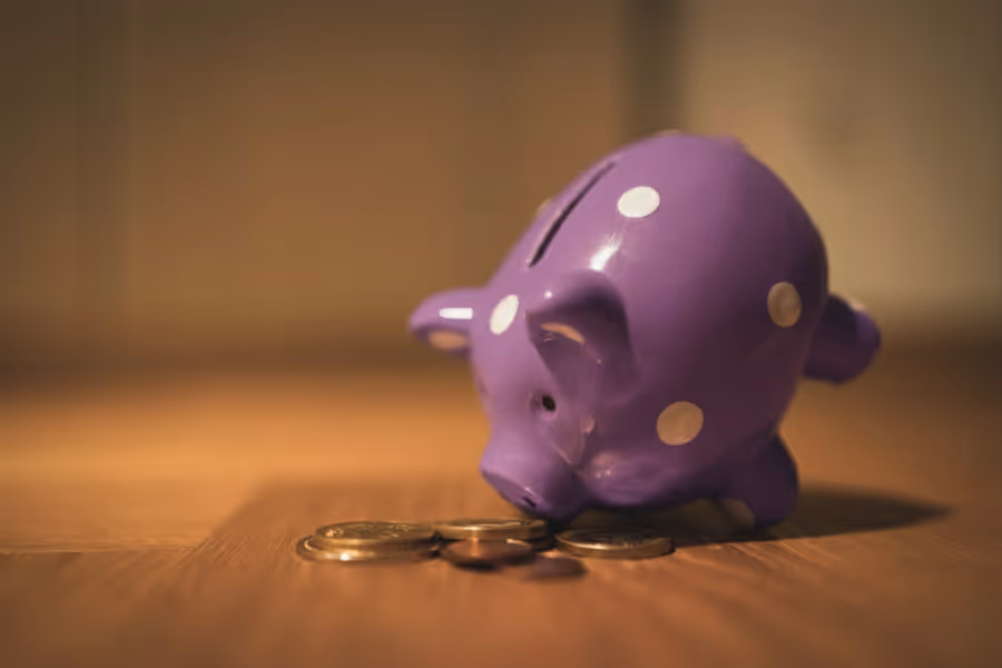 a purple piggy bank surrounded by coins