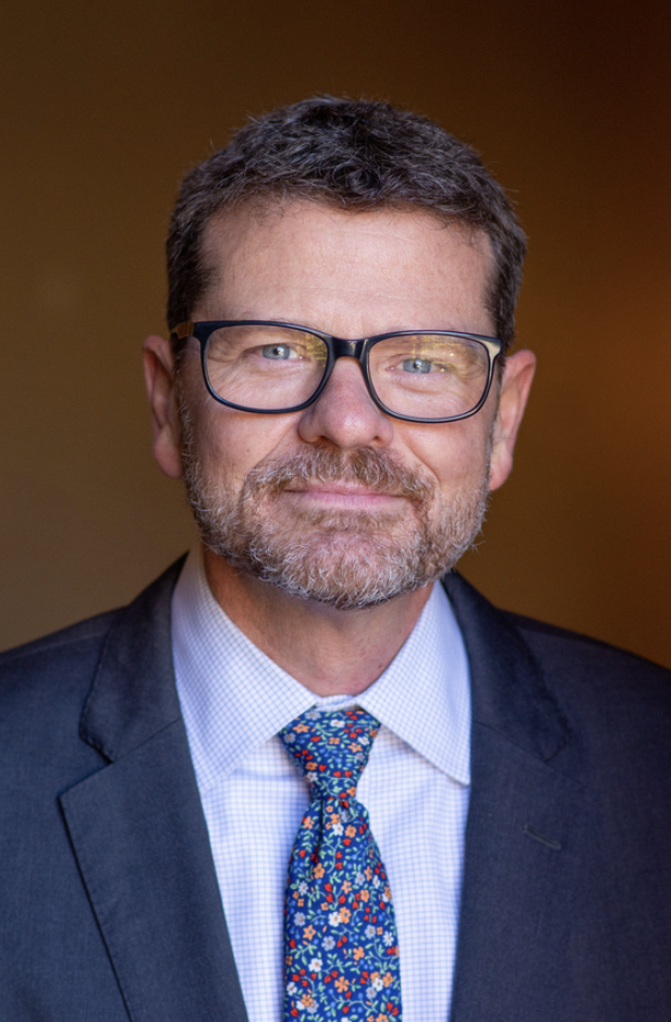 Professional headshot of Kelly McGuire in suit and tie