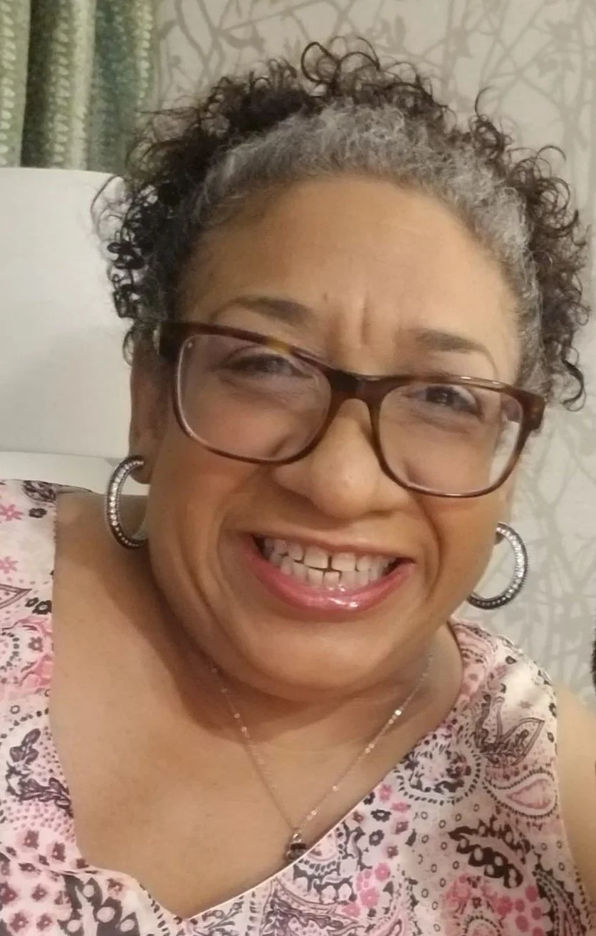 Smiling staff member wearing glasses and hoop earrings
