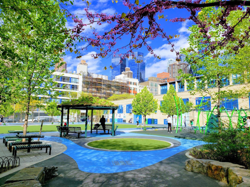 School courtyard with trees, seating area, and blue playground surface