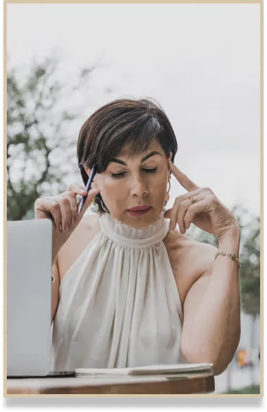 Premium virtual assistant reviewing papers with pen in hand next to laptop, showcasing executive virtual assistant services