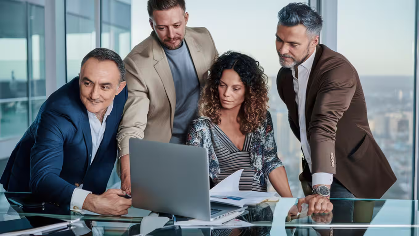 Fractional CSO consulting with three business professionals, all looking at a laptop screen during a meeting.