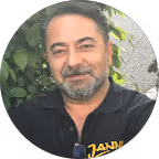 Mittelalterlicher Mann mit kurz geschorenem dunklem Haar und Bart trägt ein schwarzes Hemd, sitzt vor grünen Blättern.