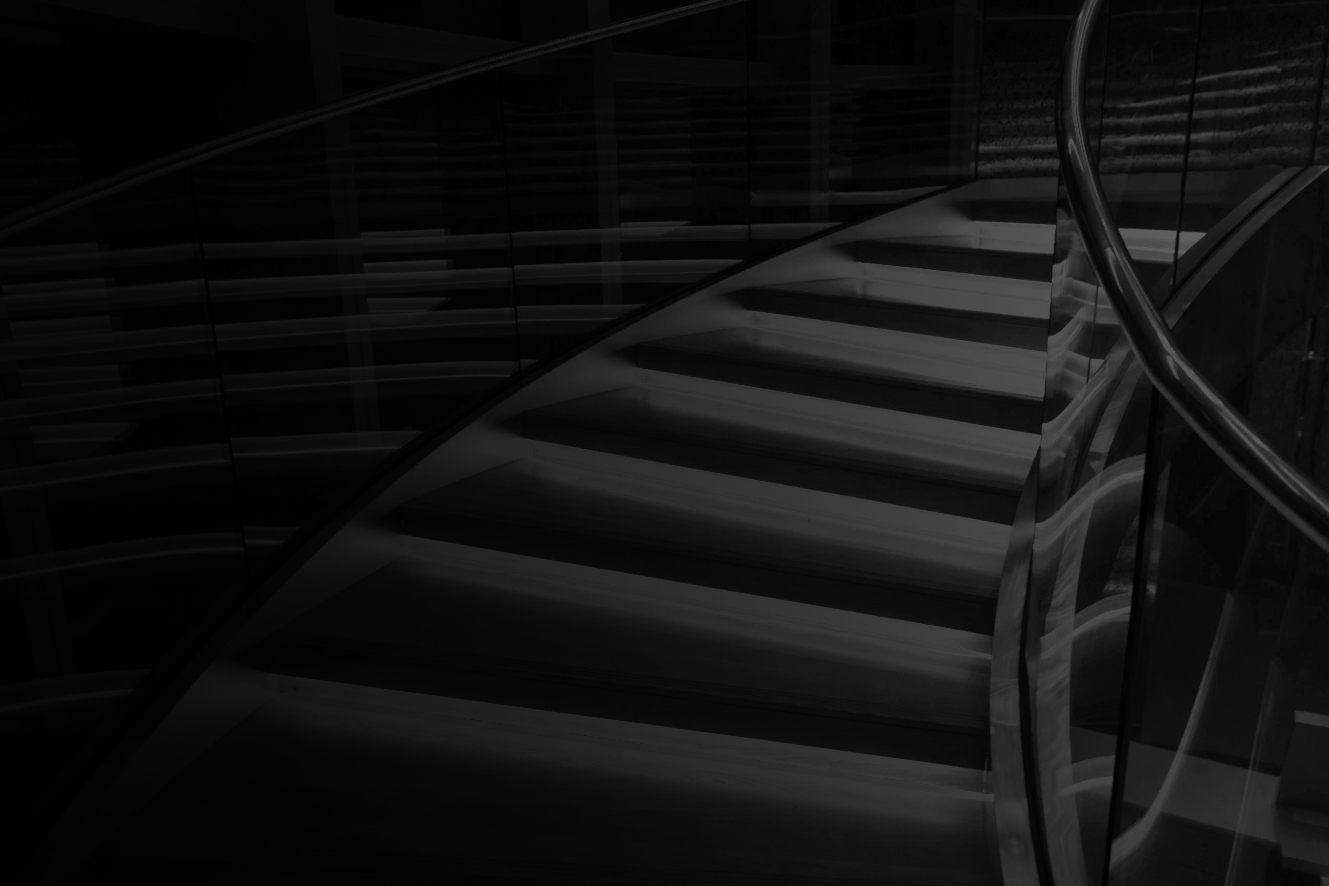 Team of rowers in yellow and black uniforms rowing together on calm water at sunset.