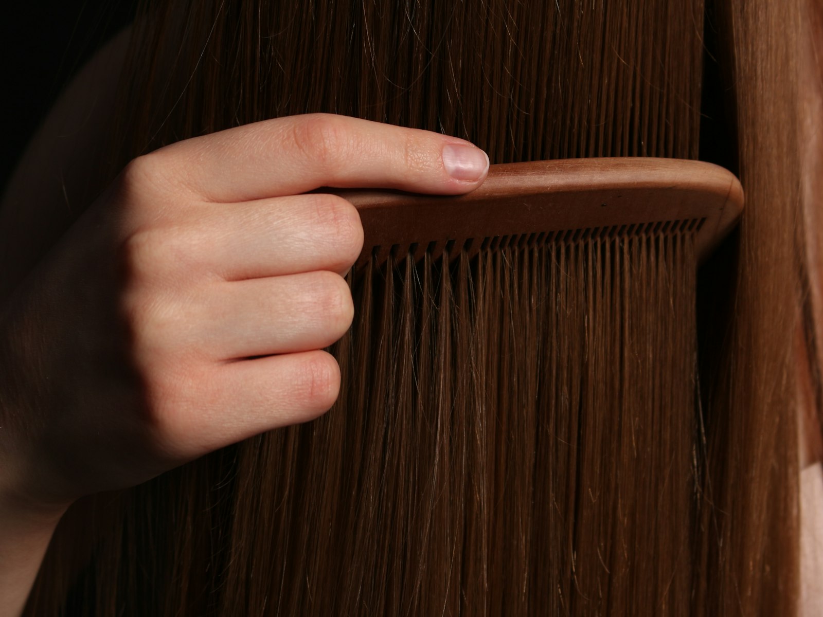 A hand combing through long brown hair