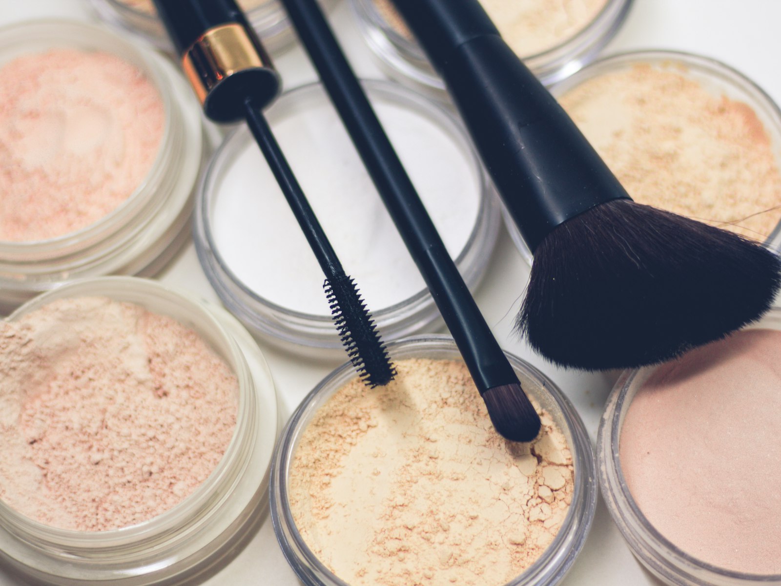Makeup brushes resting on compact powders