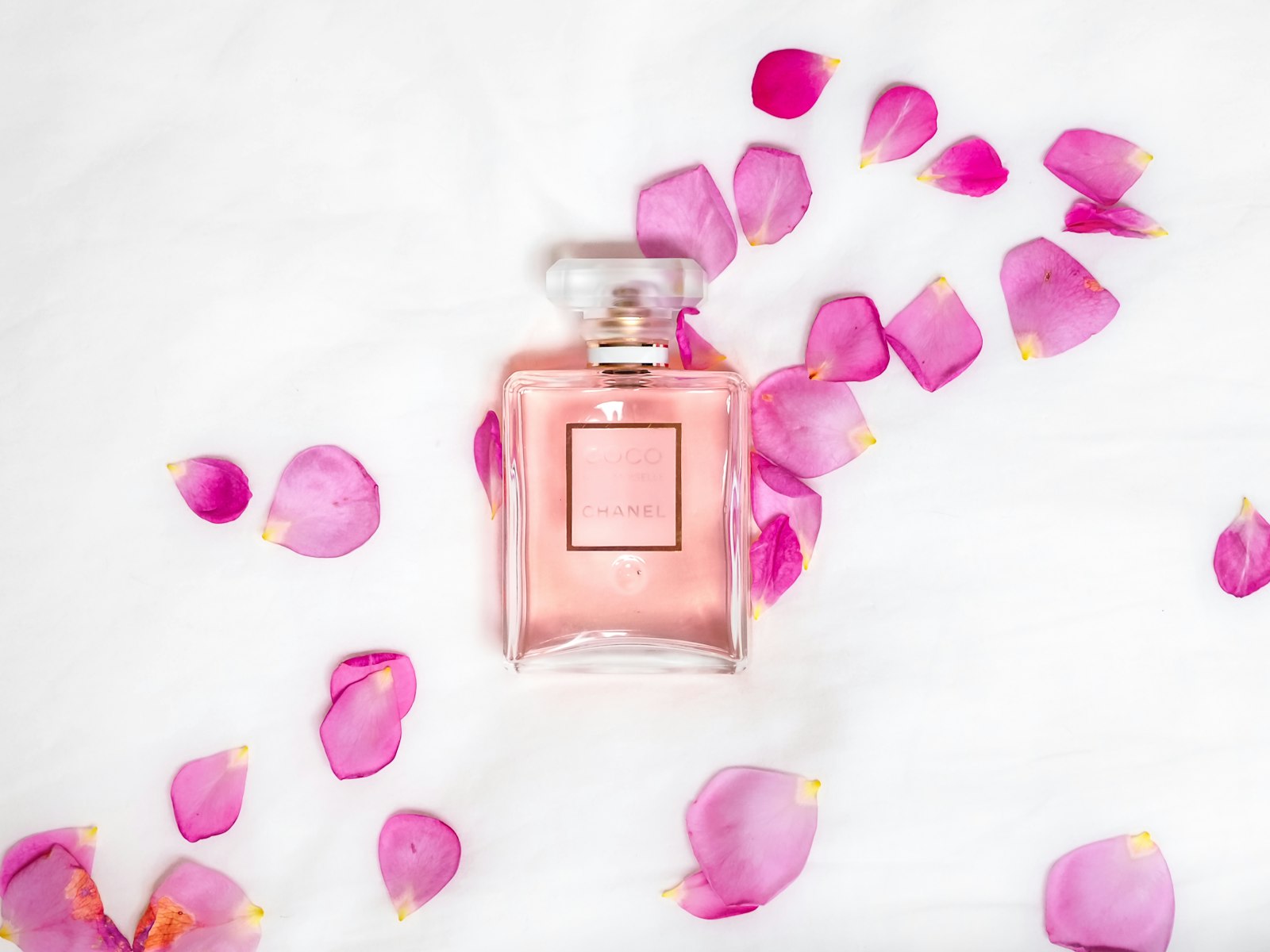 A perfume bottle surrounded by pink petals
