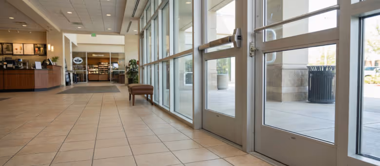 Professional commercial door and lock repair services in Calgary, featuring a high-traffic storefront entrance with aluminum glass doors and heavy-duty panic bar hardware. | Quickfix Handyman Inc.