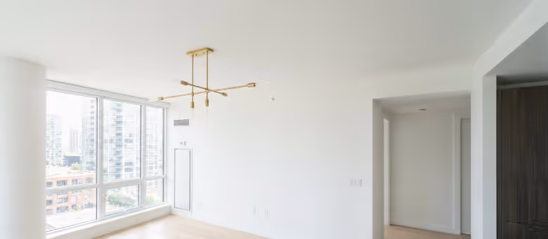 Completed lighting fixture upgrade in a modern Calgary high-rise, featuring a perfectly installed gold sputnik-style chandelier in a bright, minimalist living space. | Quickfix Handyman Inc.