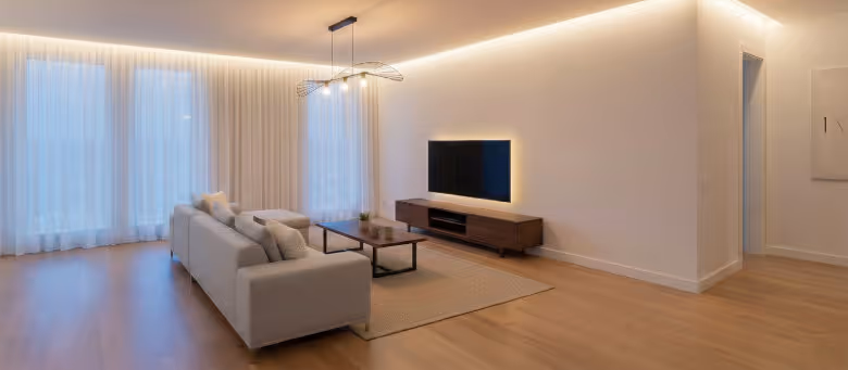 Professional indoor electrical services in Calgary, featuring custom LED cove lighting and ambient TV backlighting in a modern, minimalist living room. | Quickfix Handyman Inc.