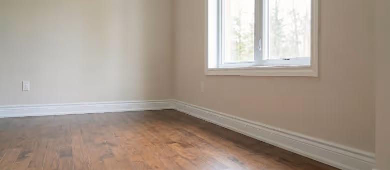 Completed baseboard and trim installation project in Calgary, featuring flawlessly installed white colonial-style baseboards that perfectly finish the hardwood flooring | Quickfix Handyman Inc.