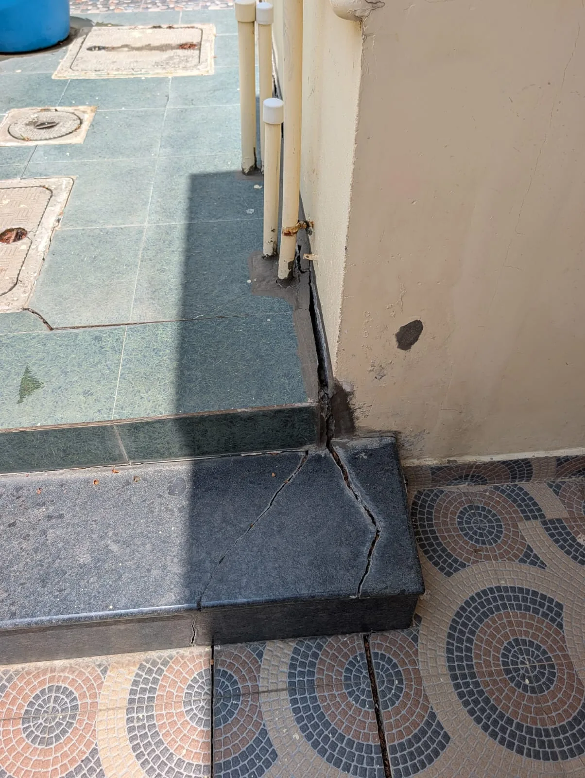 Tile flooring settlement and gap at building perimeter indicating sub-base consolidation