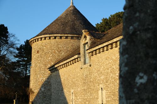 La tour ronde et la façade en pierre du château de Trémohar à la lumière du soir