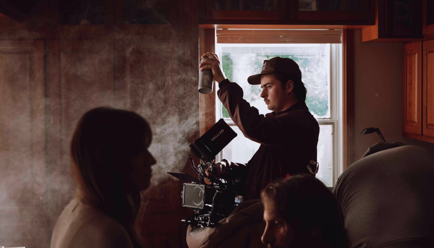 Videographer filming a dancer in a dark studio lit with blue and pink neon lights.