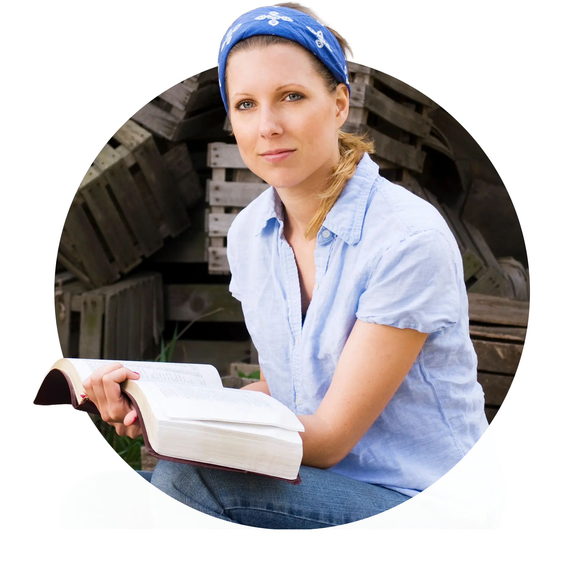 Woman wearing blue headband and light blue shirt sitting and reading a thick book outdoors.