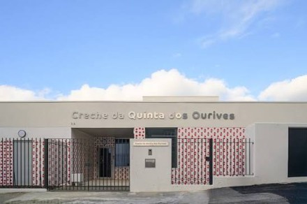Reception area of a school with colorful desk labeled 'A NOSSA EQUIPA' and educational photos on walls.