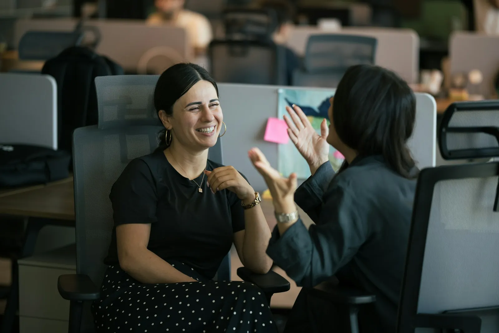 Two colleagues laughing together at their desks