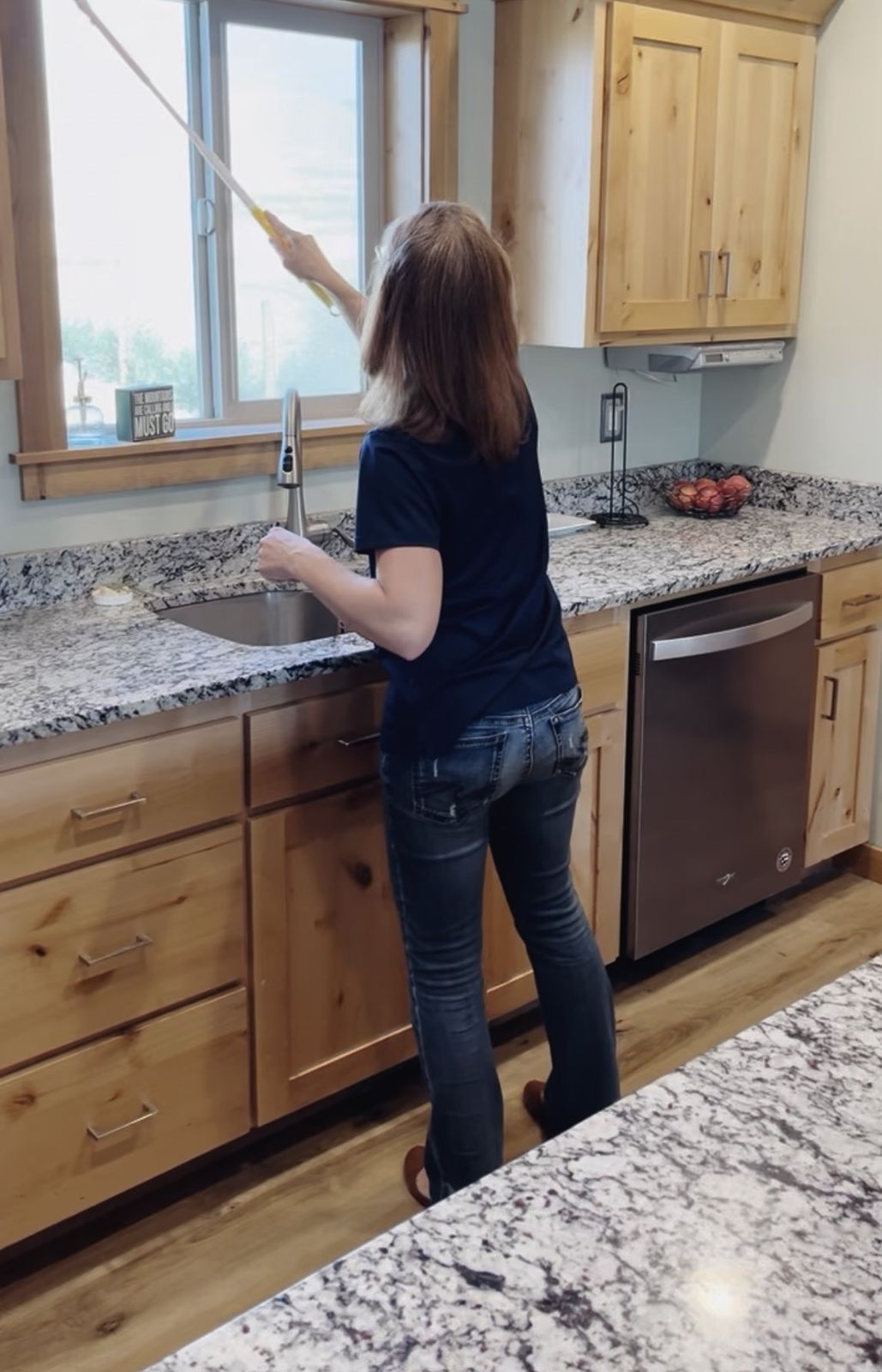 Dusting a kitchen window during a house cleaning