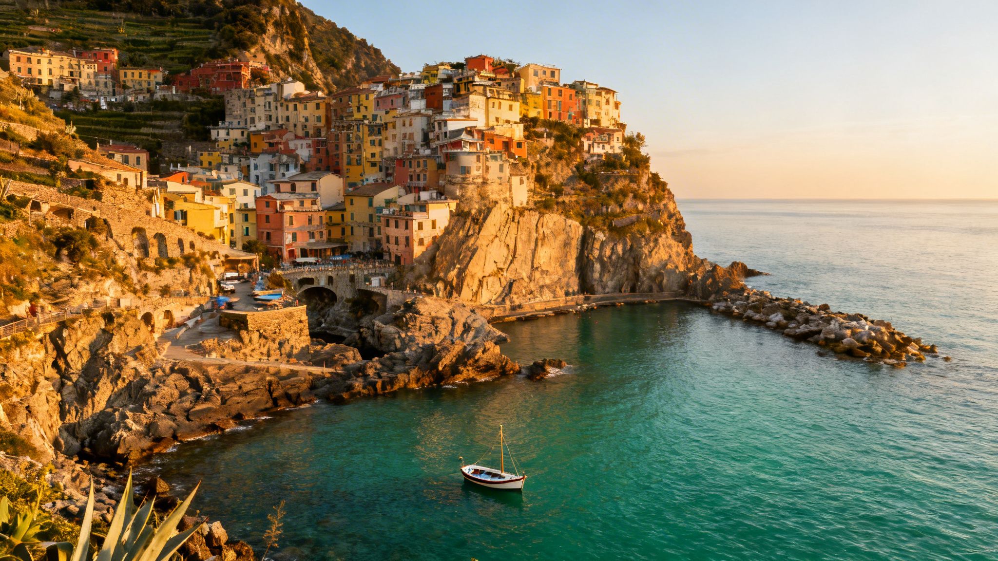 Colorful coastal village of Manarola, Cinque Terre, Italy, built on cliffs overlooking the turquoise sea at sunset.