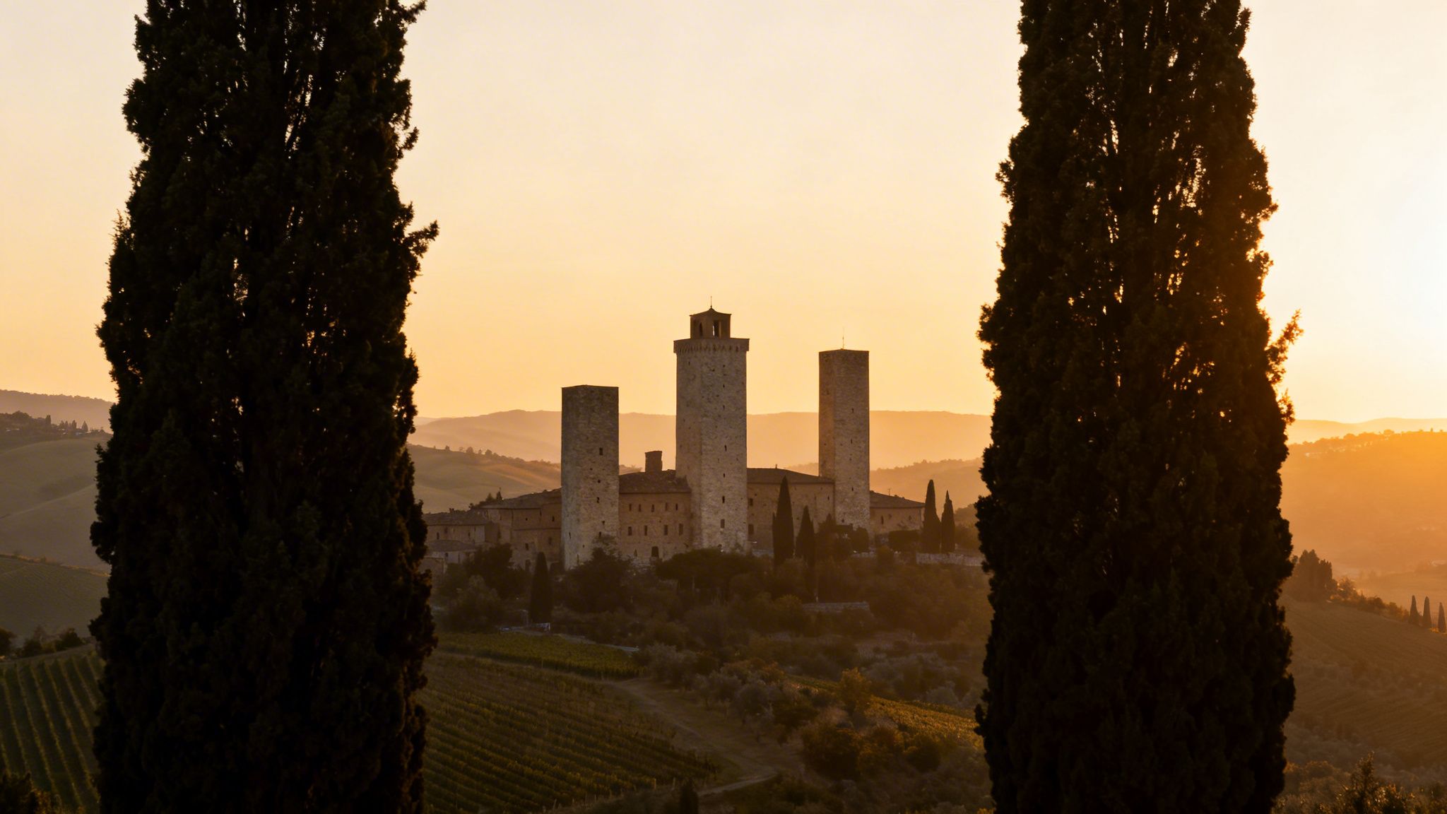 San Gimignano medieval towers framed by cypress trees at golden sunset over Tuscany.