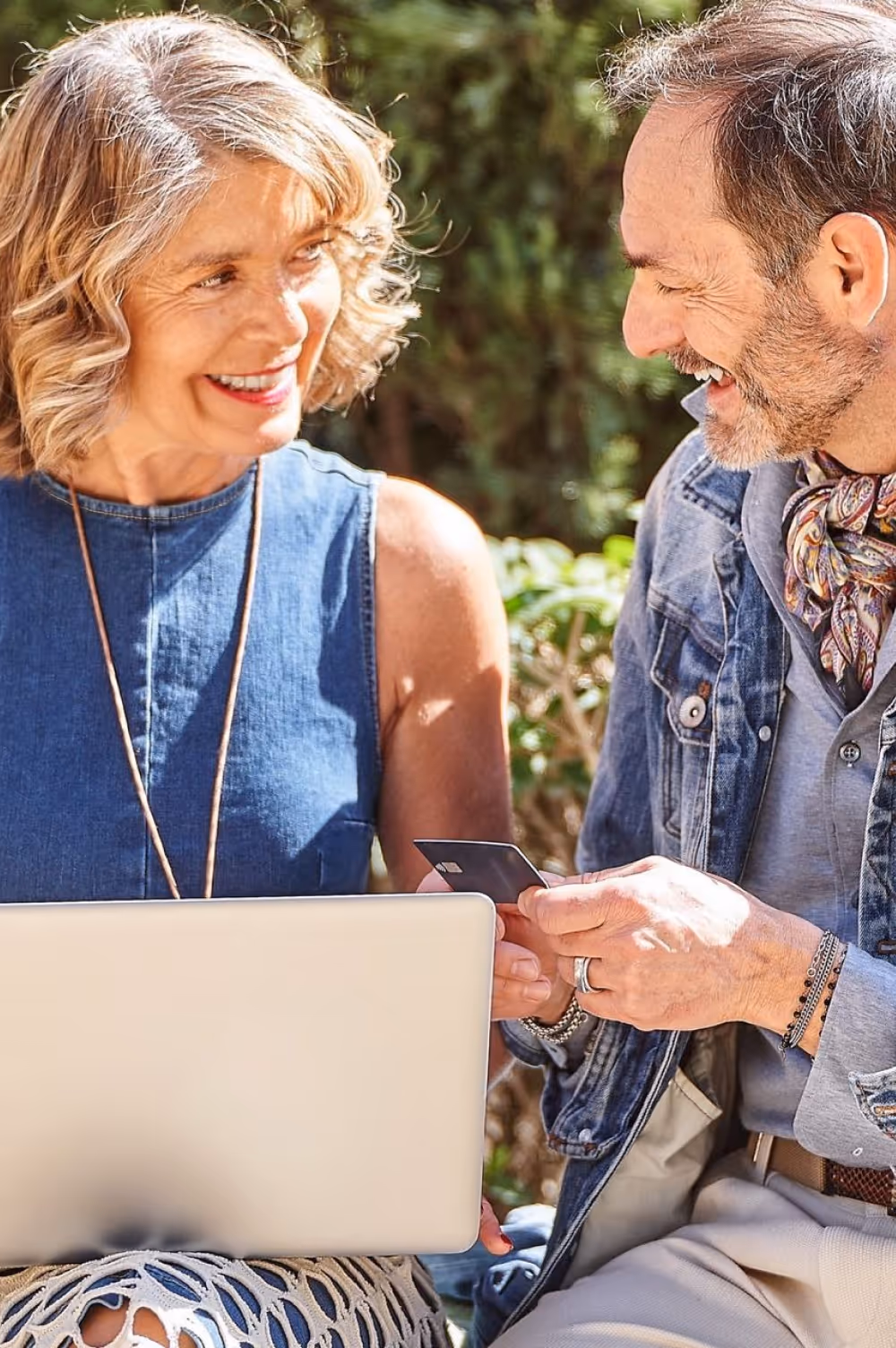 Couple sitting outdoors with a laptop representing wellness and lifestyle management.