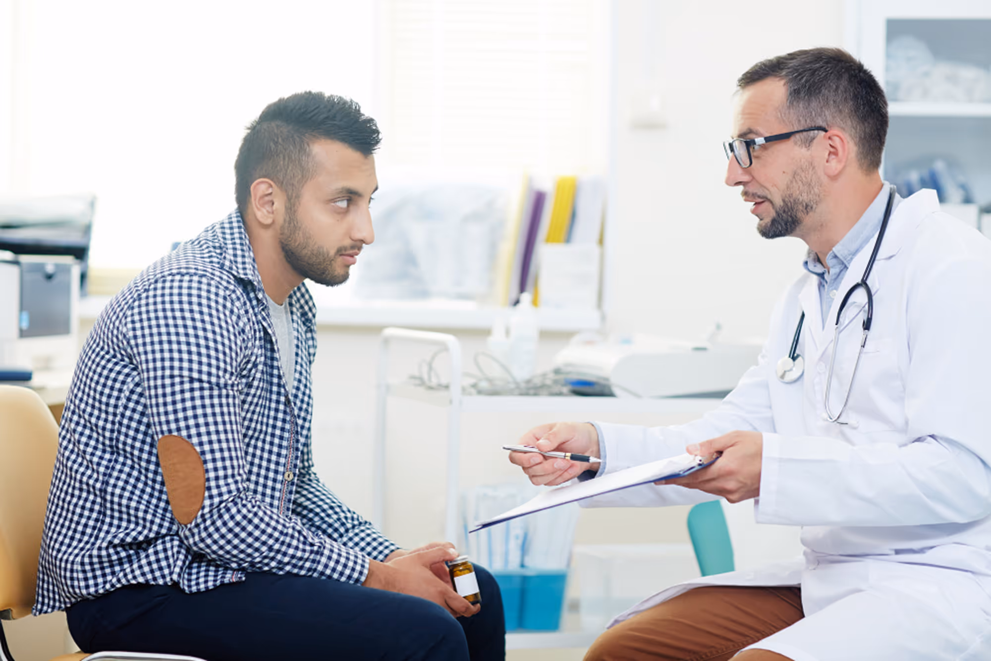 Male patient and urologist discussing health concerns during a clinical consultation at a desk.