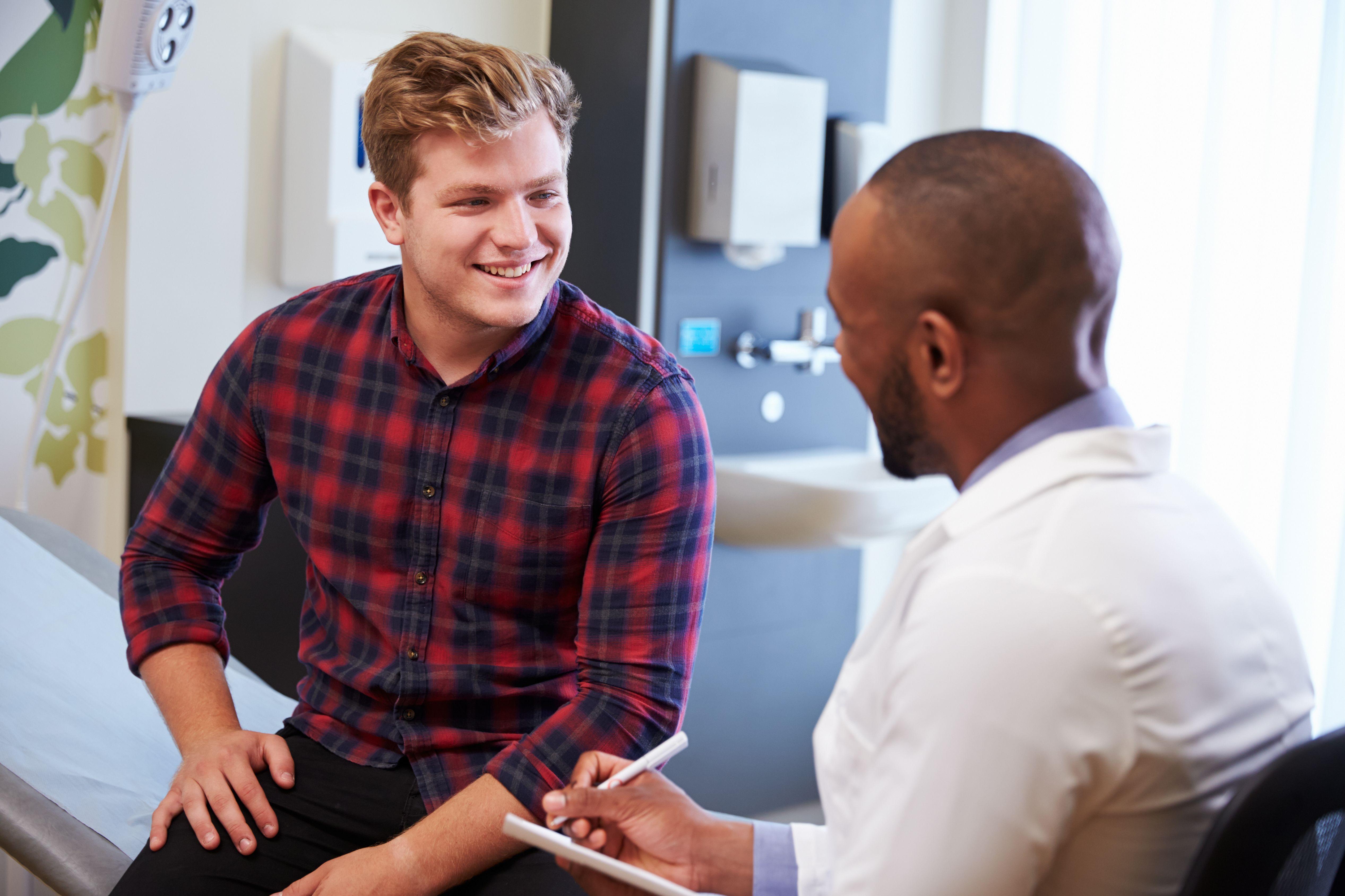 Male patient smiling at male urologist office while doctor takes notes