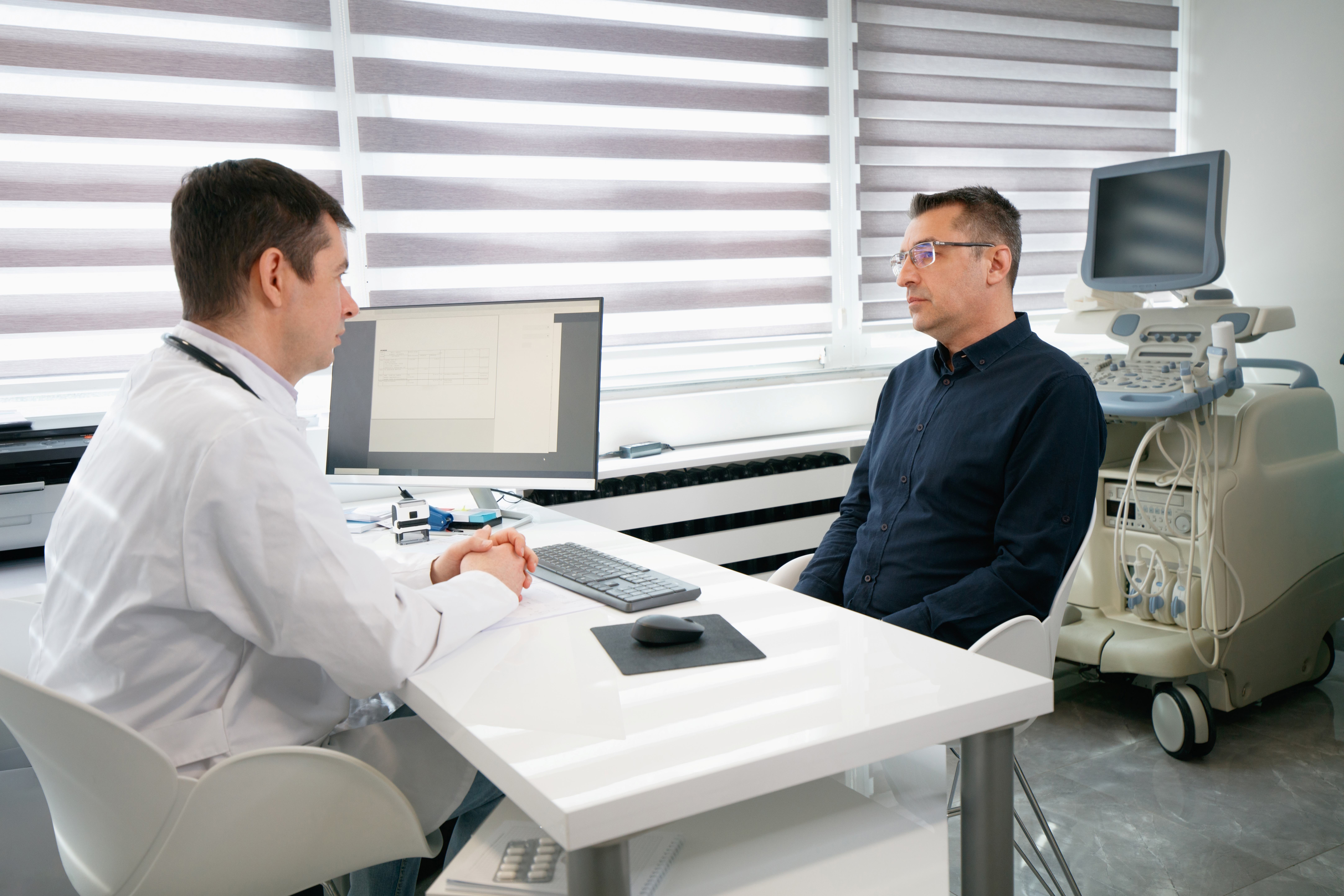 Urologist meeting with male patient at desk to go over results and next steps