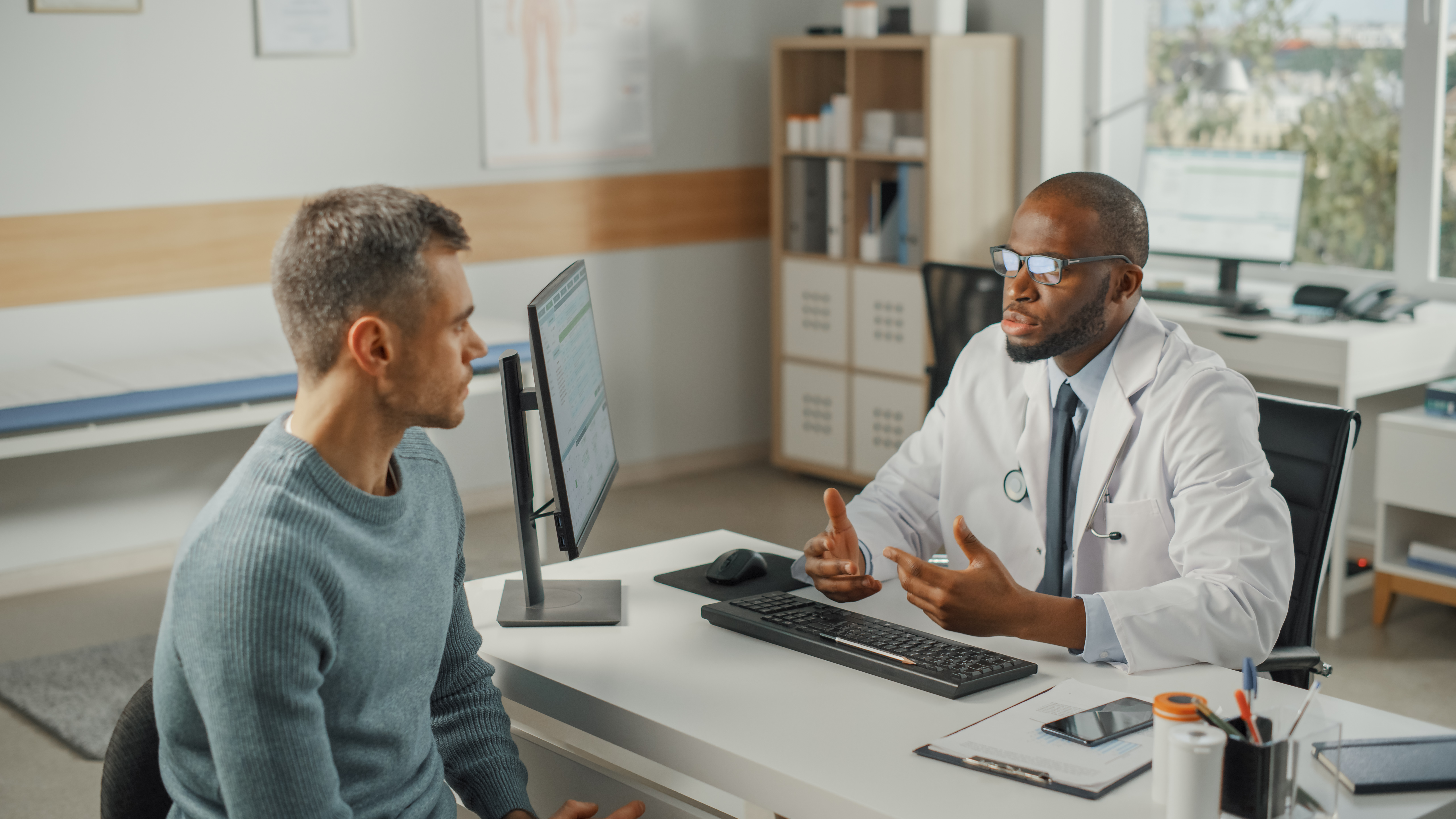 Urologist sitting at desk with male patient discussing in office procedures available