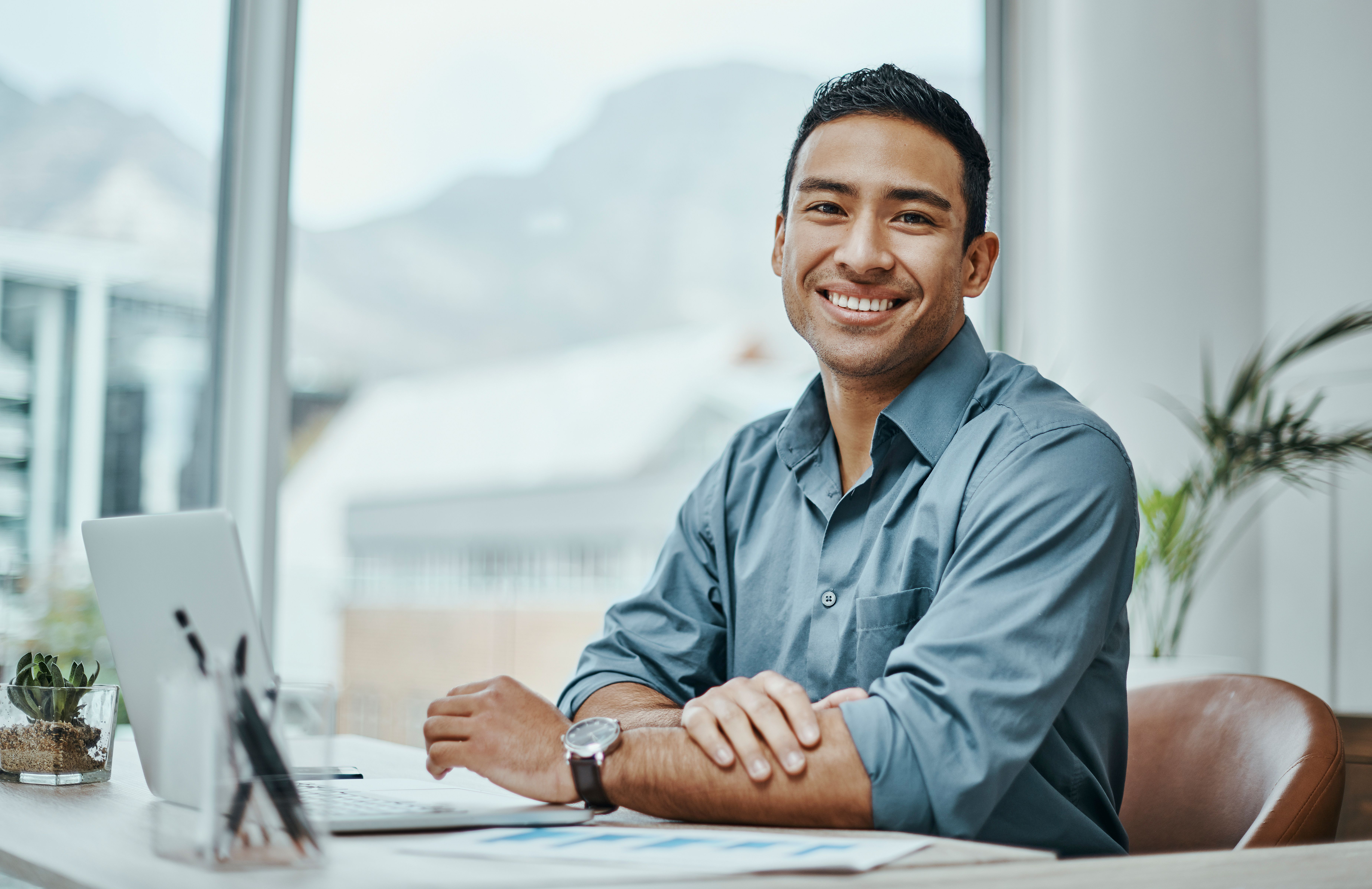 Male sitting at his desk with a computer smiling