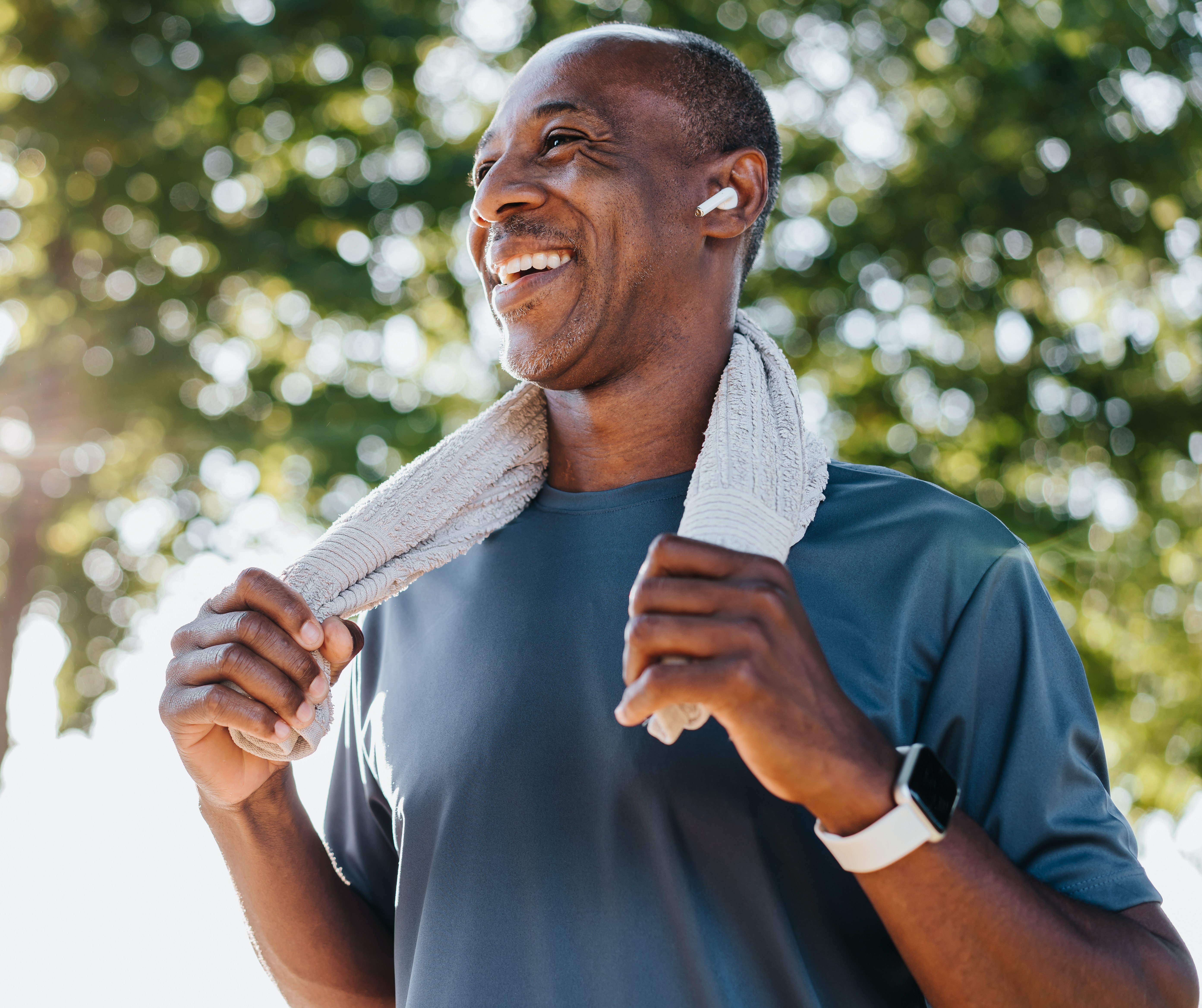 Male outside smiling with towel around his neck after workout 