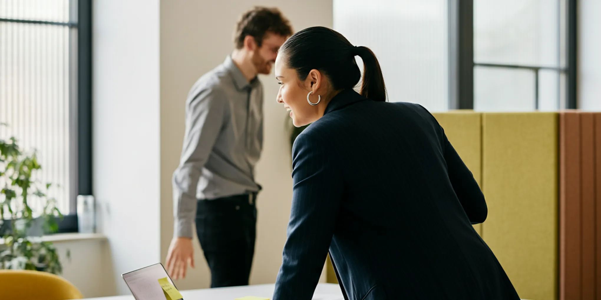 Two colleagues working together in front of a computer screen in an office.