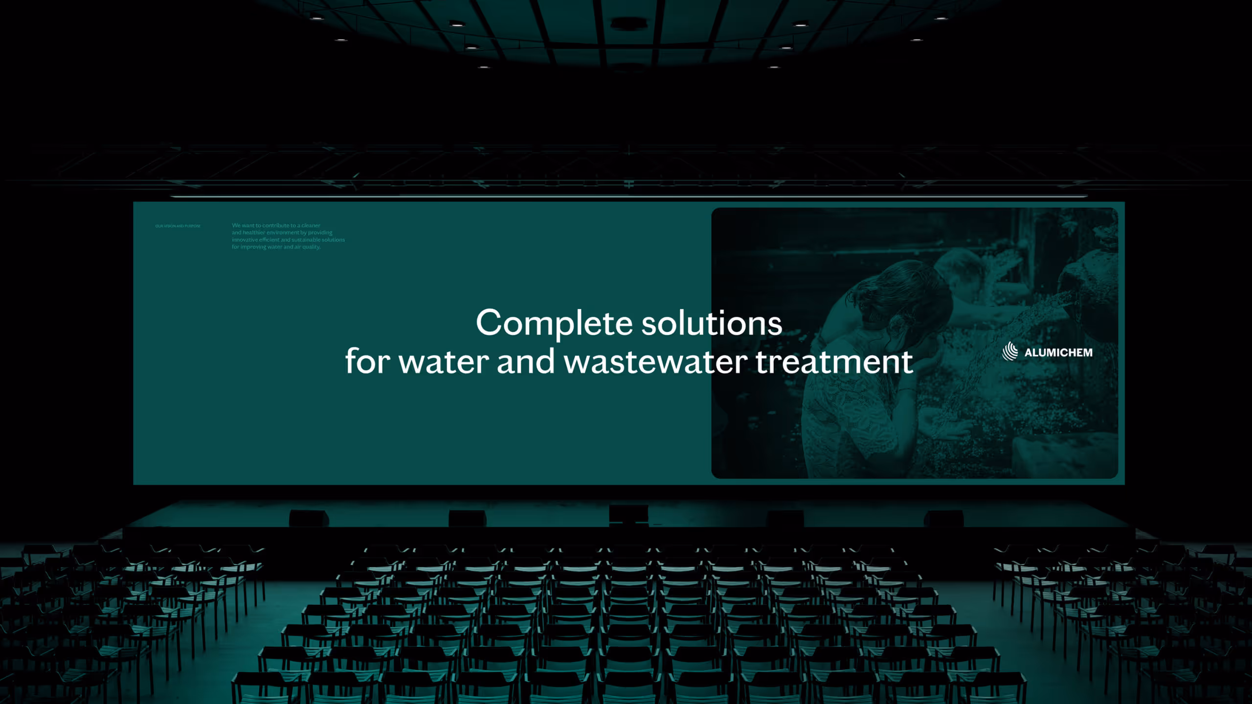 Conference stage with a large screen displaying 'Complete solutions for water and wastewater treatment' and a faded image of children washing at a water source.