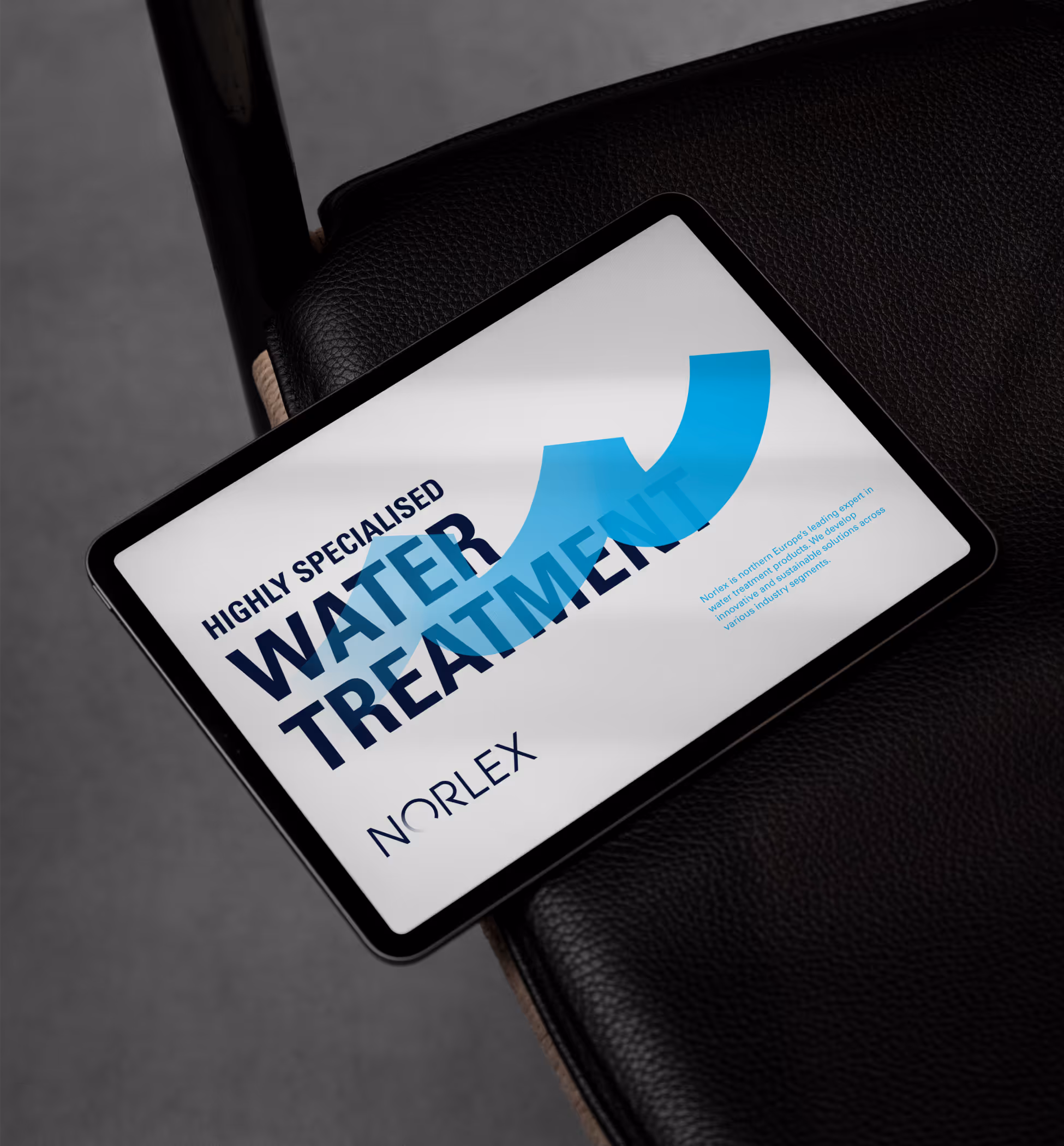 Tablet on a black leather chair displaying a Norlex advertisement for highly specialised water treatment.