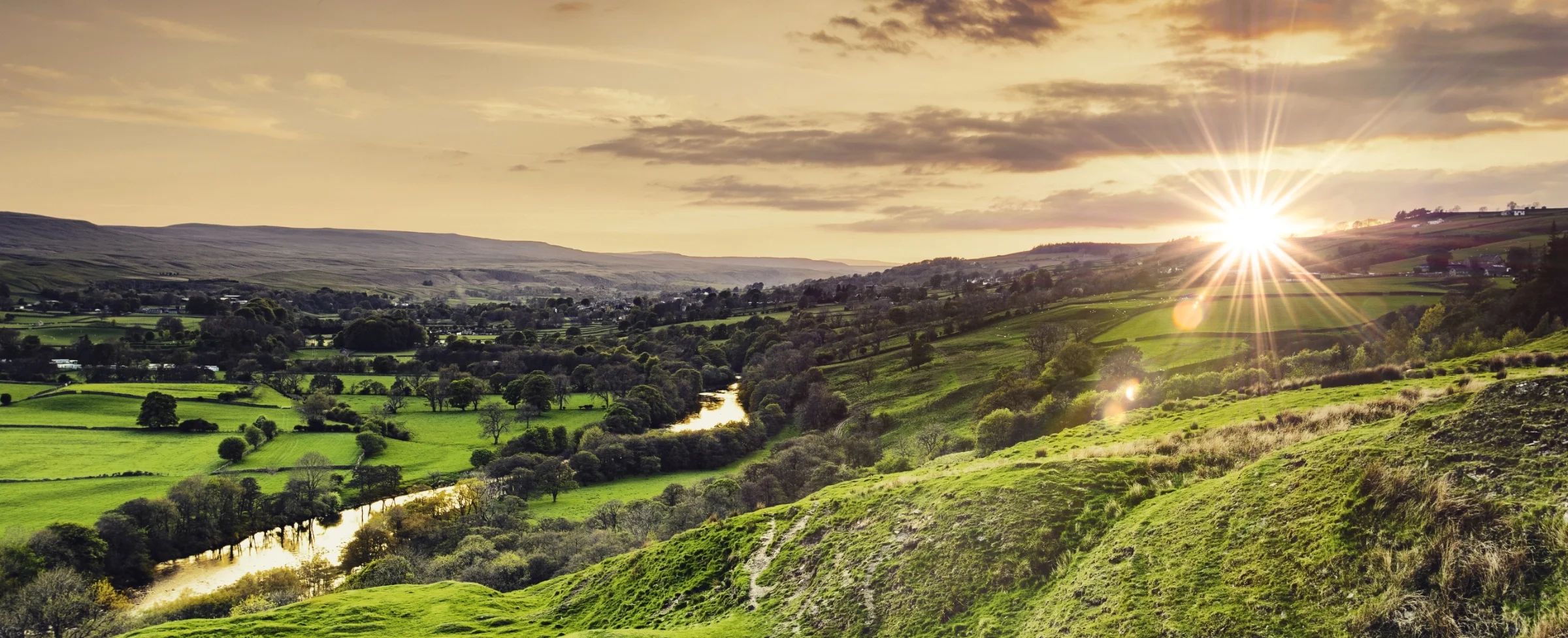 Sunset over green rolling hills near to Eggleston in Teesdale and the winding river Tees in a rural landscape.