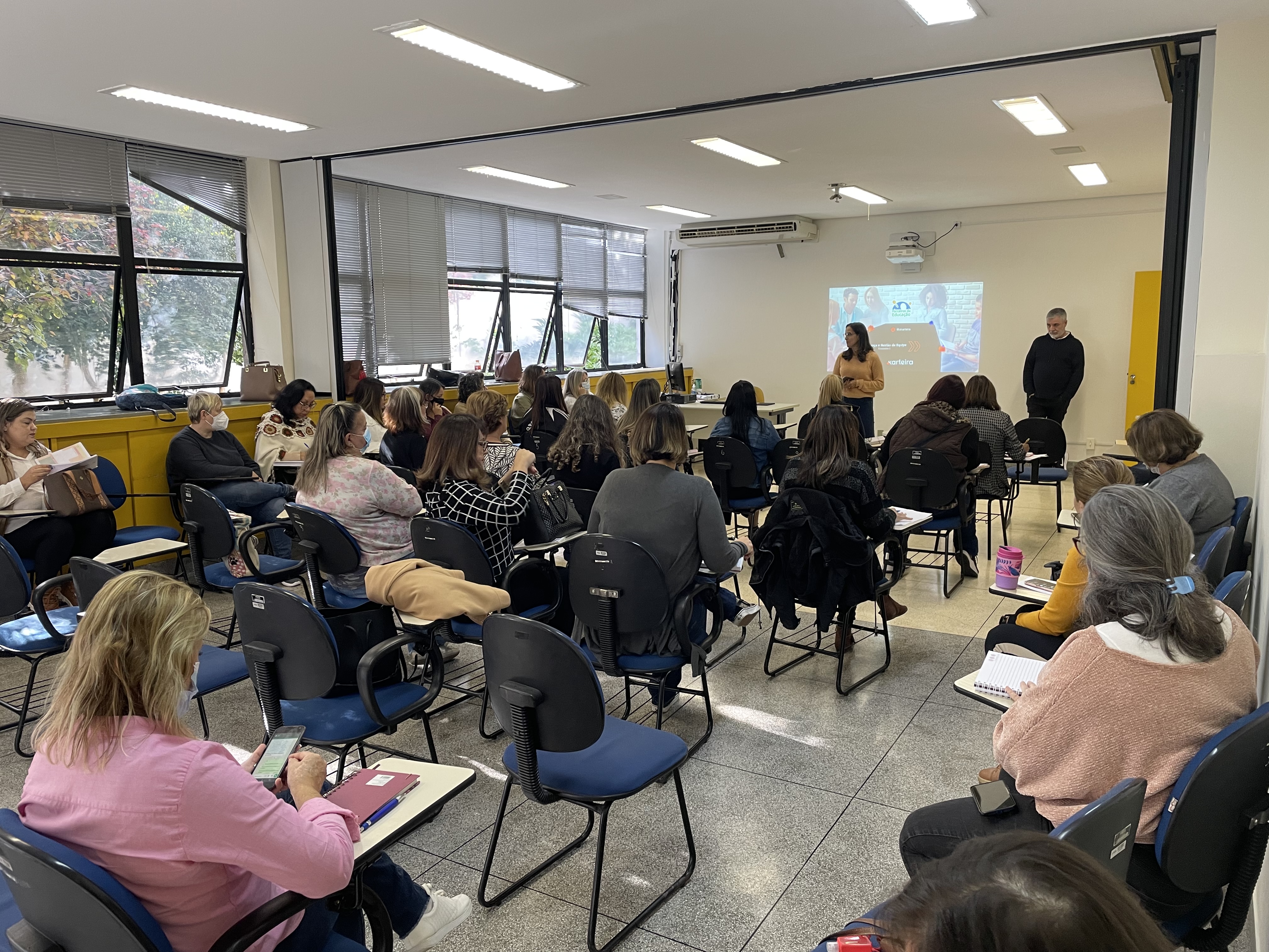 Grupo de professores em auditório assistindo palestra de capacitação pedagógica da Karteira.