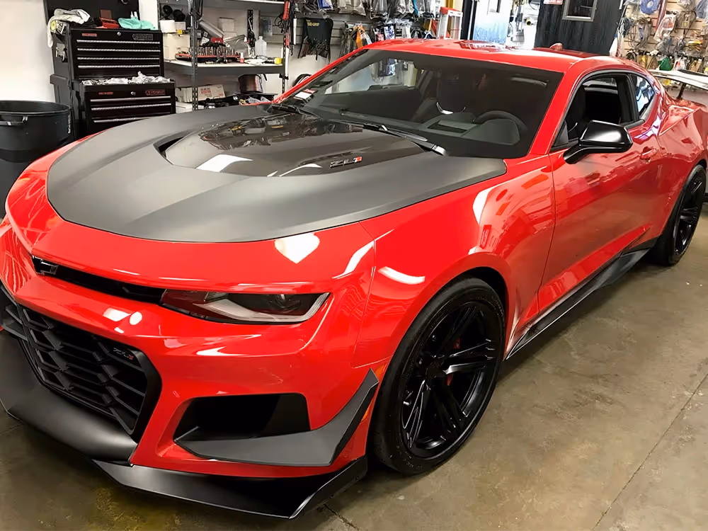 Red Chevrolet Camaro with custom hood and exterior performance upgrades completed by our vehicle upgrade shop.