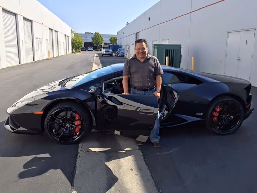 Upgraded black Lamborghini sports car showcased outside a vehicle upgrade shop.